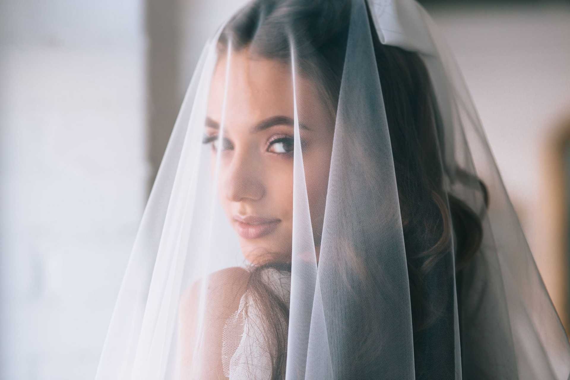 Bride with a delicate veil, softly gazing over her shoulder.