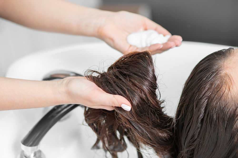 Washing hair with shampoo in a salon sink, focusing on soap and wet hair.