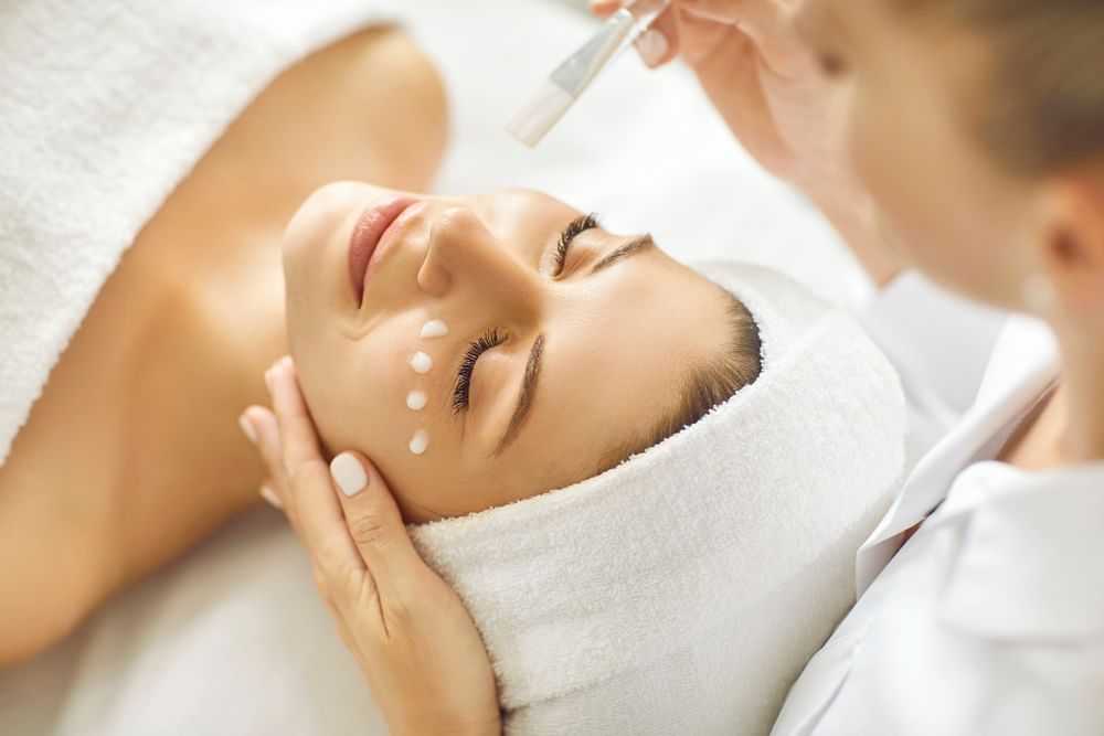Facial treatment with cream applied to a relaxed woman in a spa setting.